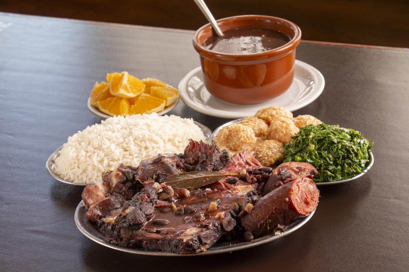 Feijoada completa servida com arroz, couve, farofa, torresmo e laranja